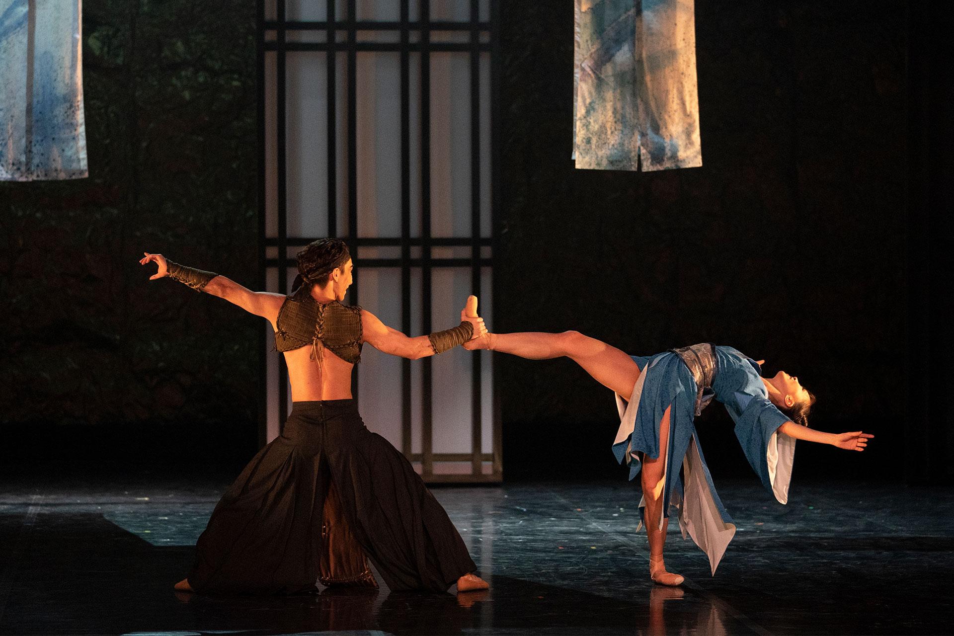 Takeda holds Okichi's raised leg while she bends backwards