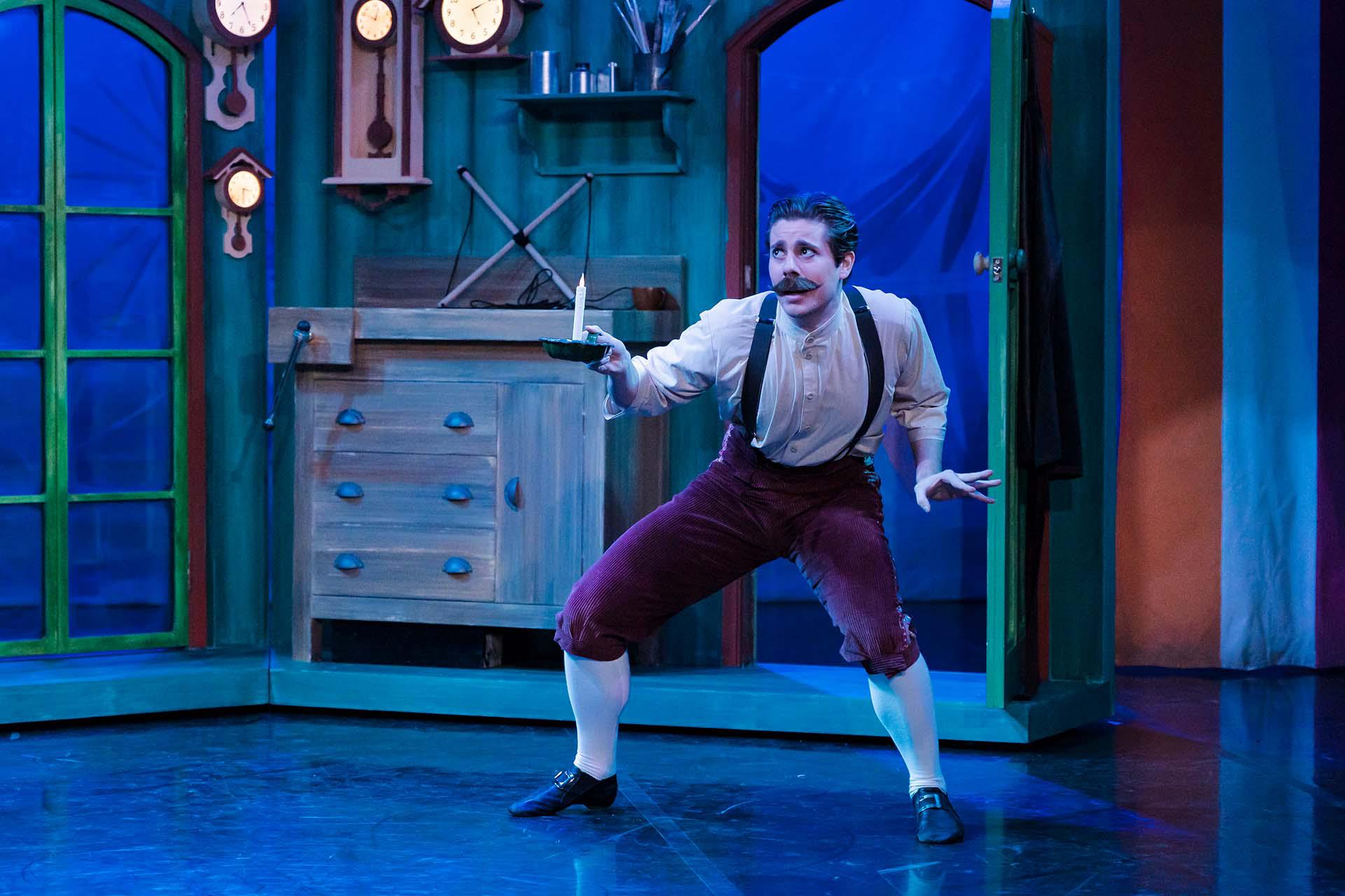 Geppetto looks warily through his workshop while holding a candle.