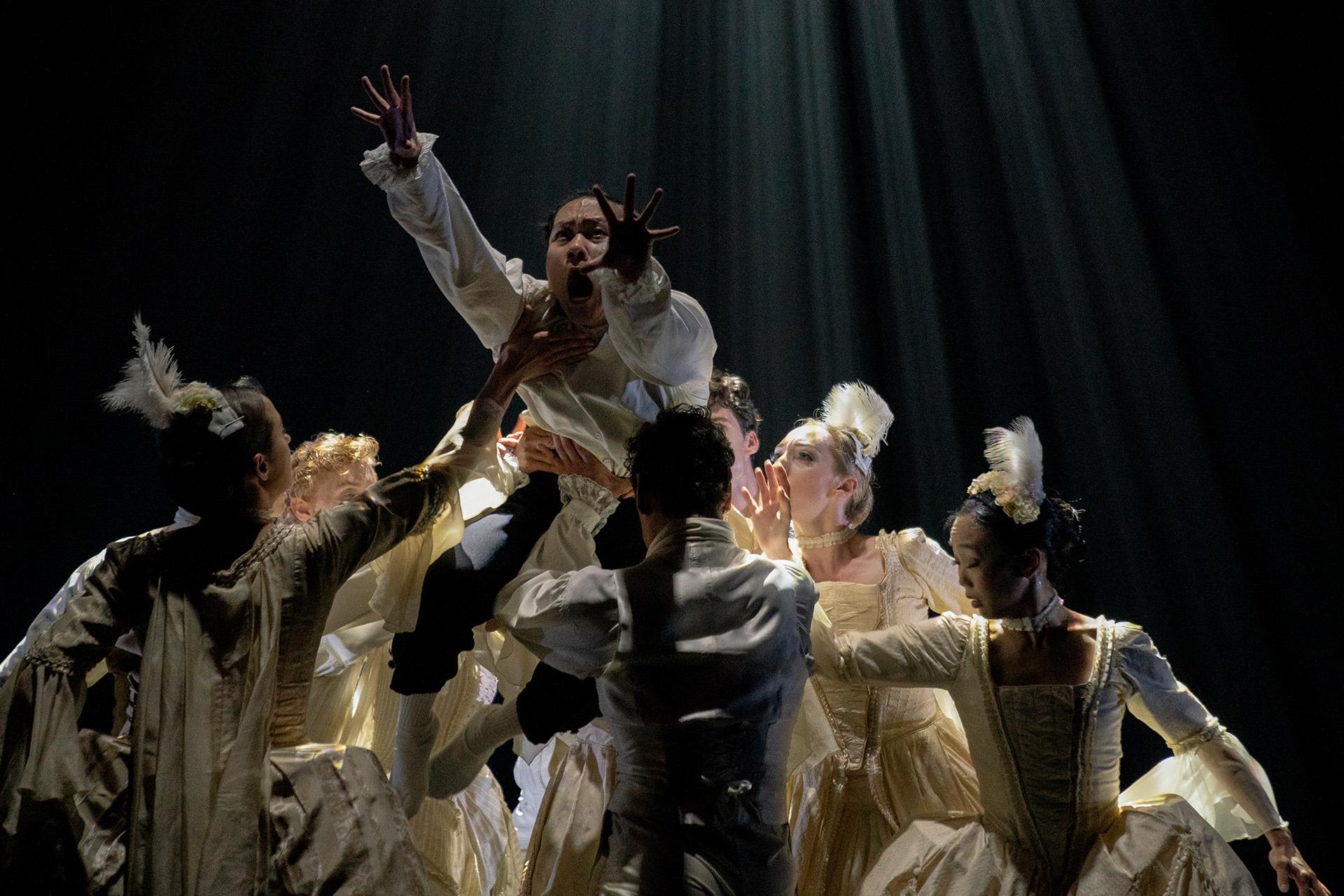 A man stands in a group of people, he is screaming and reaching to escape