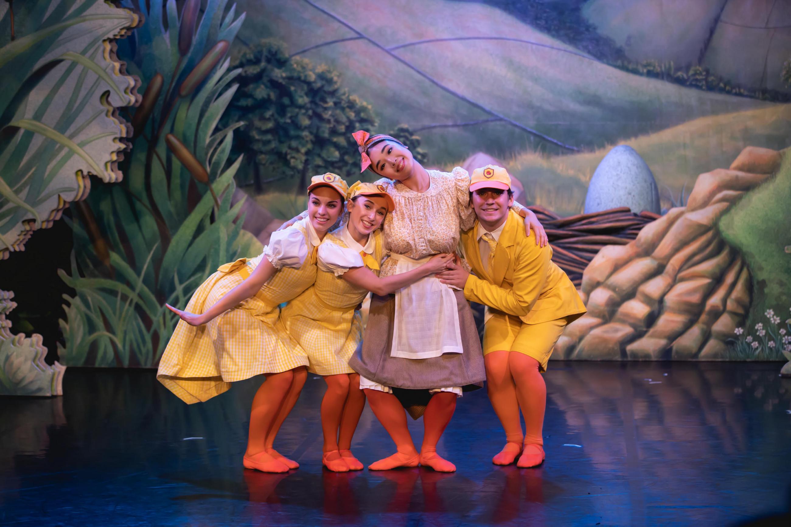 Three dancers dressed as ducklings hugging another dancer dressed as a Mother Duck