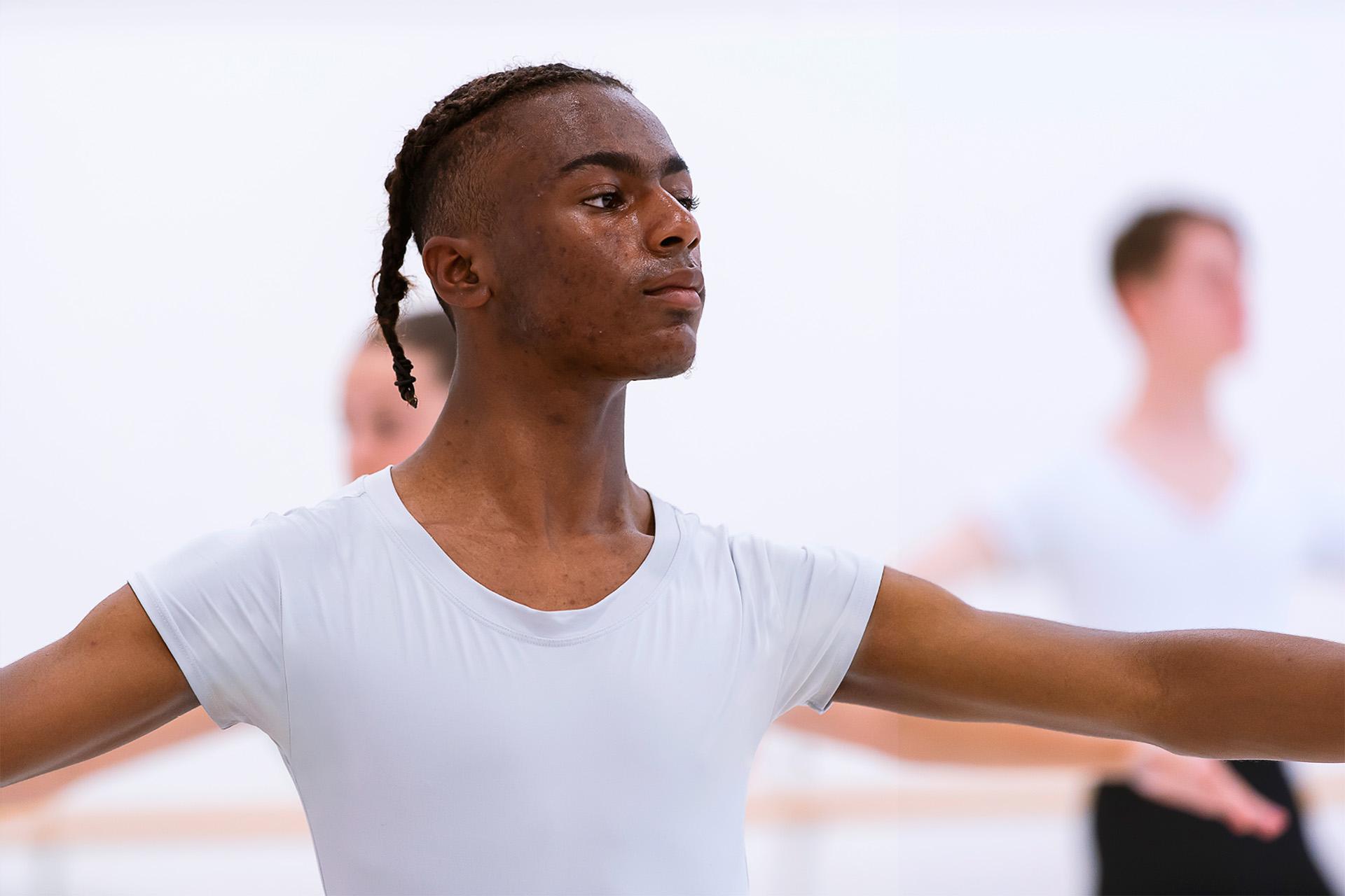 Male Academy student in a white T-shirt with his arms outstretched
