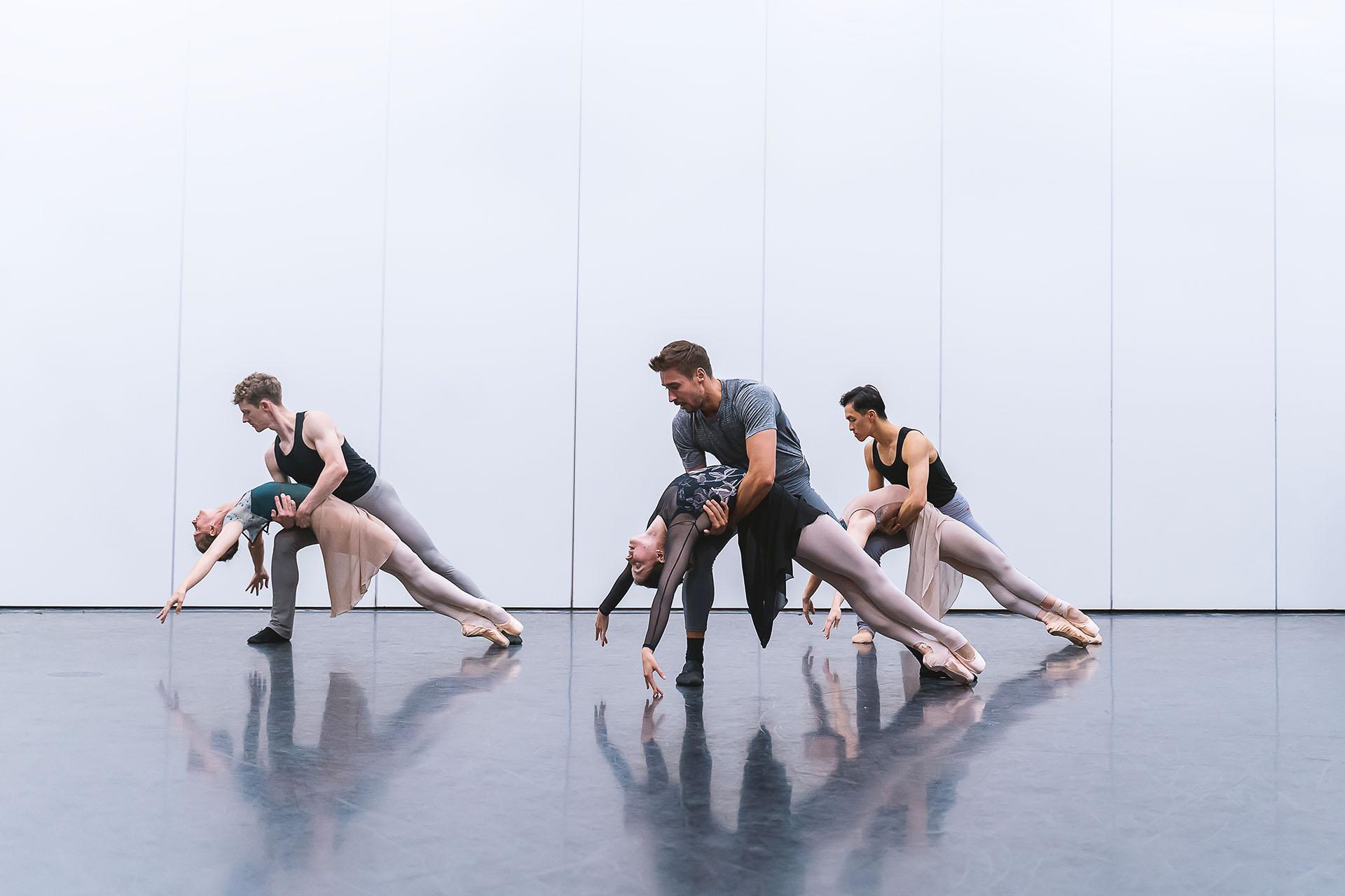 Three male/female couples him supporting her by the waist as she as she leans back, draped over his hold and en pointe.