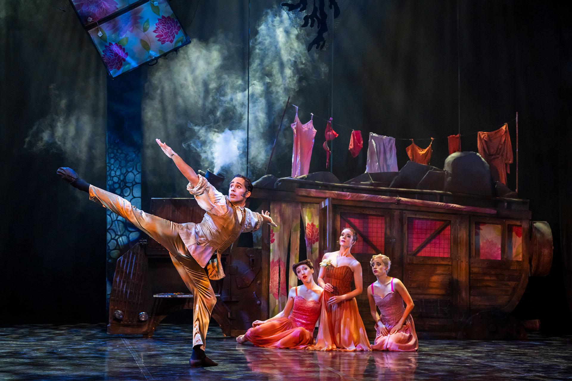 Beauty's father dances to show his encounter with the Beast while Beauty and her sisters kneel and look on