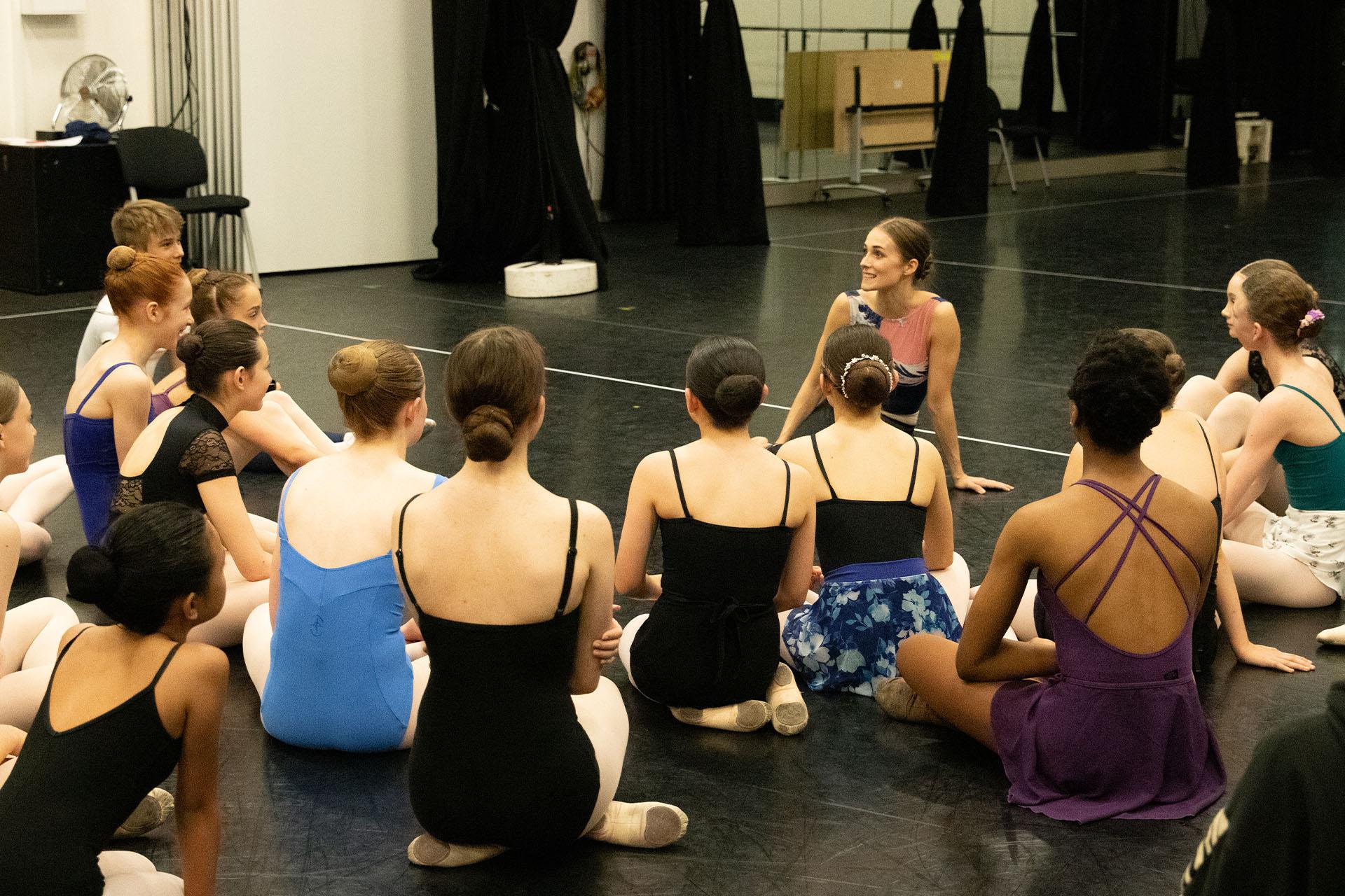 Dancer sat down talking to ballet students