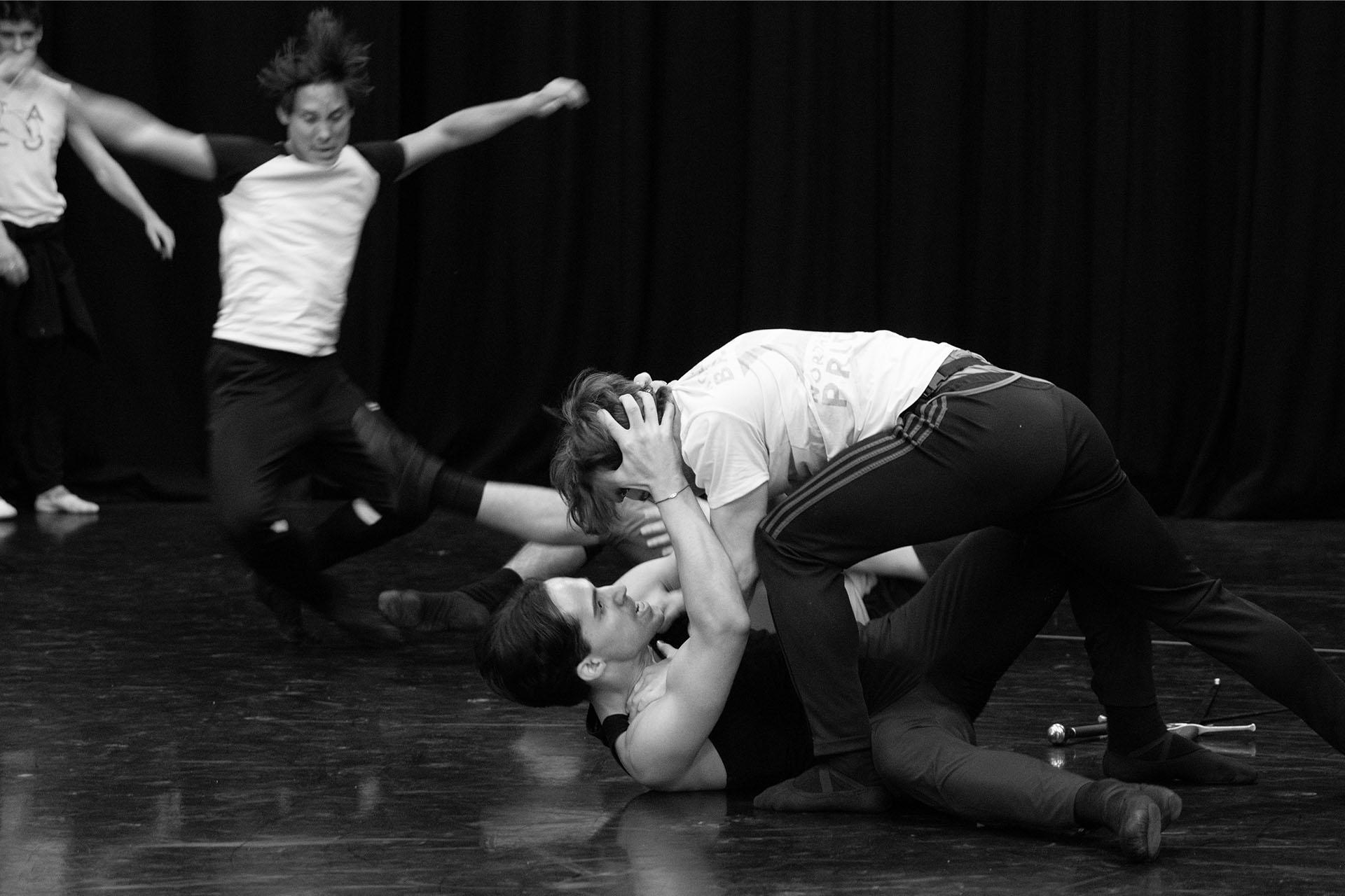 Black and white photo from rehearsals with two men on the floor fighting
