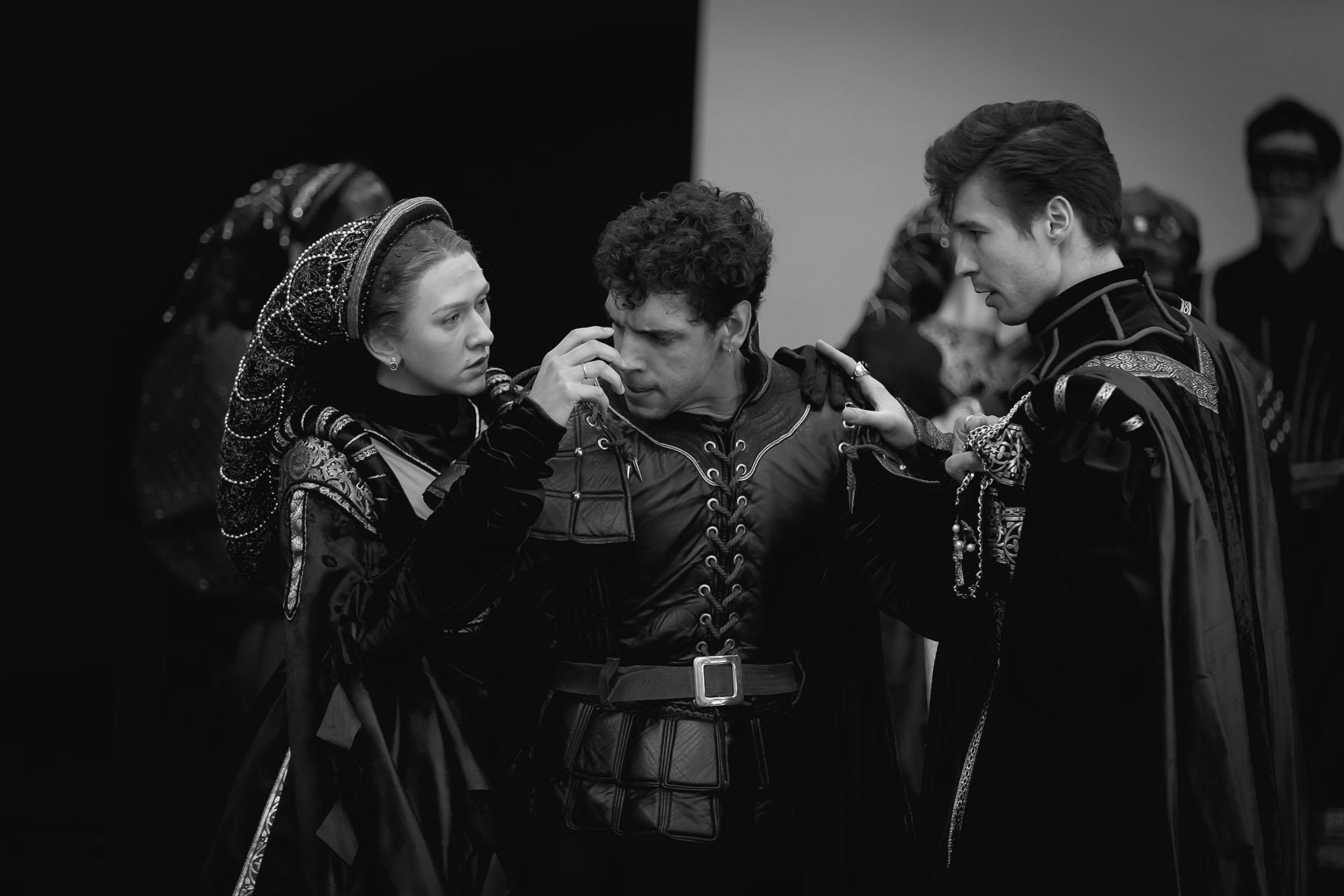 Black and white photo a an man with a angry, pained expression being held back by two people who seem to be concerned