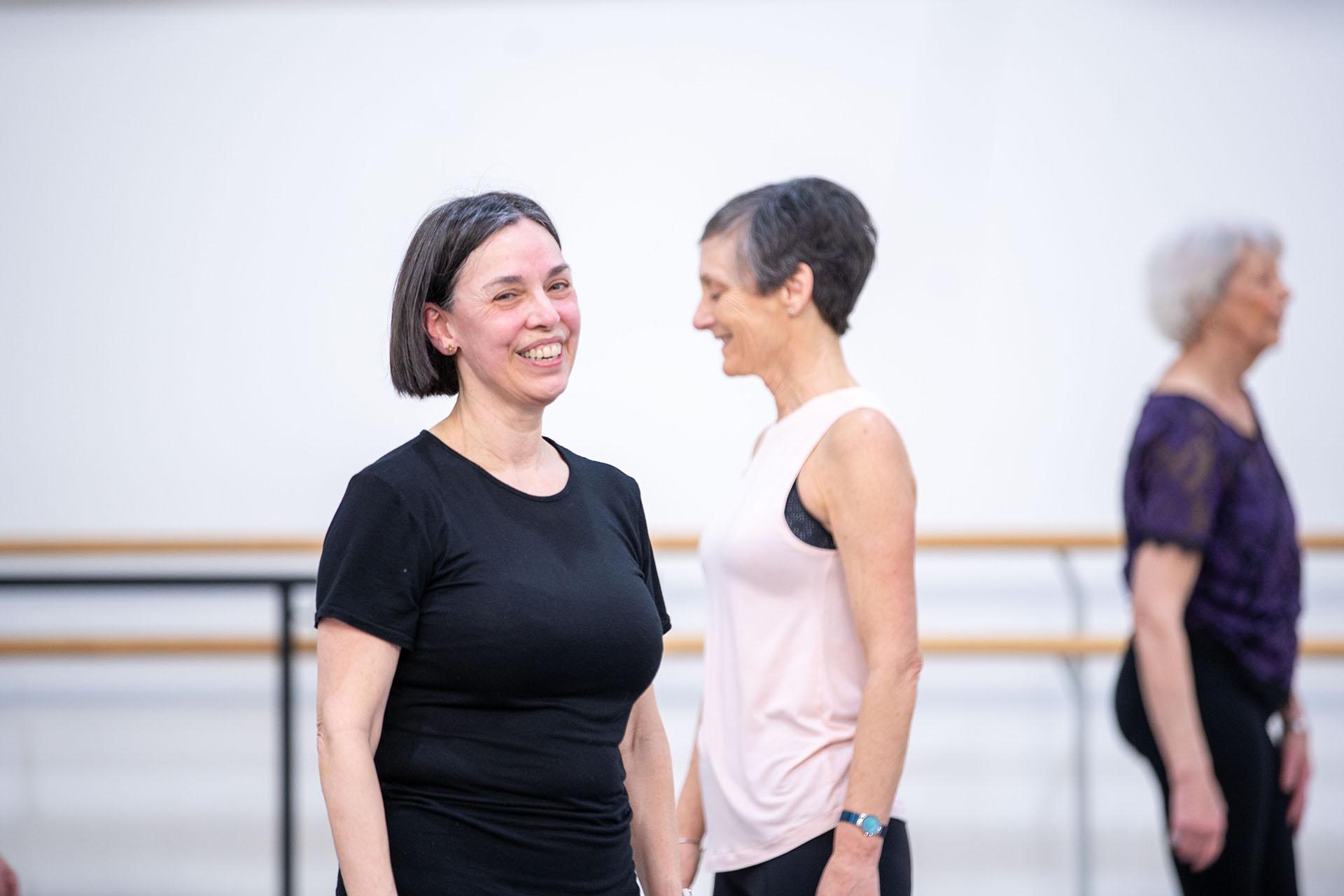 Smiling woman in black T-shirt preparing for the next steps in her ballet class