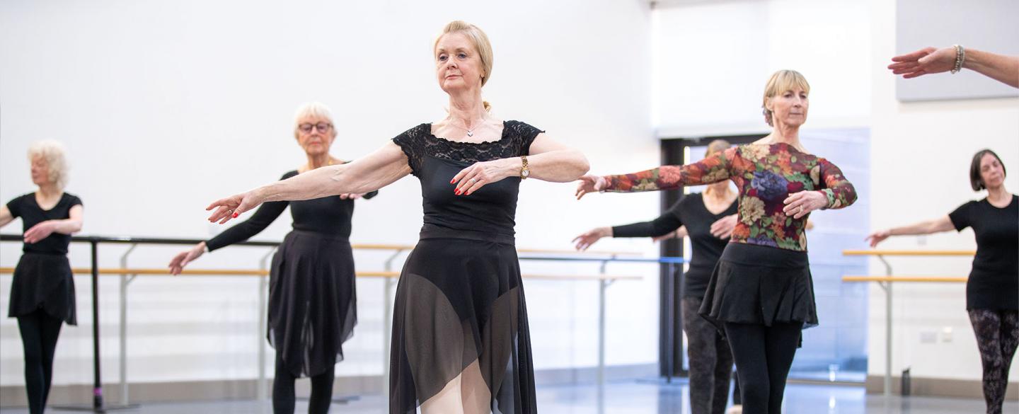 Class of dancers each in a classic ballet pose during a lesson