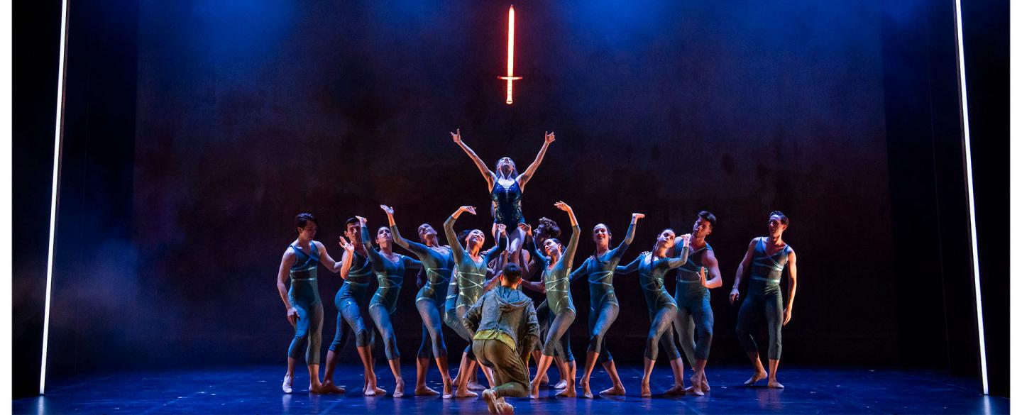 The Ladt of the Lake held aloft by dancers representing the waters raises her arms to the glowing sword just above her head