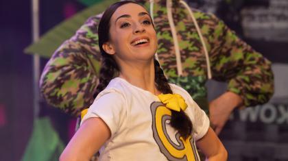 Gretel smiling broadly wearing a white T-shirt with her first initial emblazoned in yellow