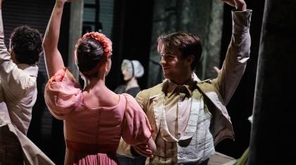 Two dancers facing each other, one arm clasping the others, their other arm raised behind them