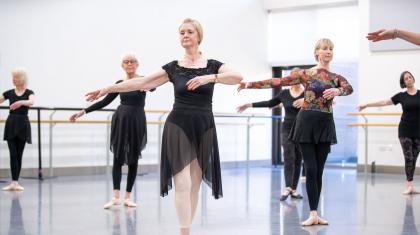 Class of dancers each in a classic ballet pose during a lesson